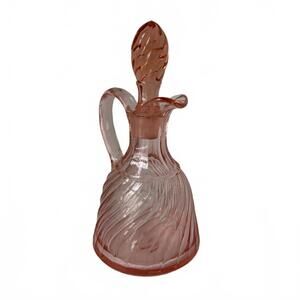 A pink swirled glass cruet with a decorative stopper and handle.